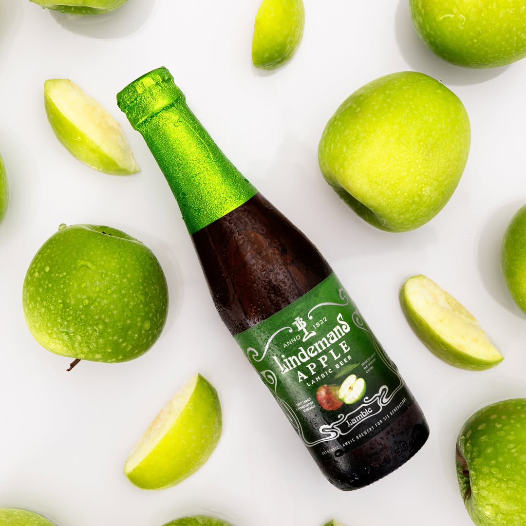 Bouteille de bière Lindemans Apple sur fond de pommes vertes fraîches, packshot rafraîchissant
