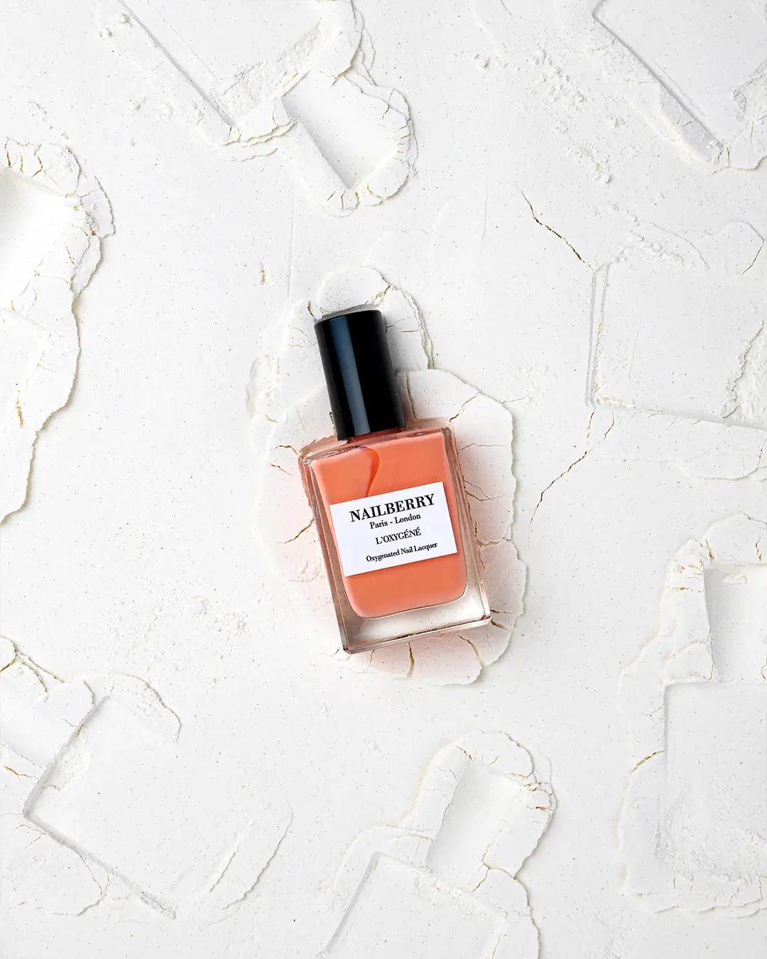 Vernis Nailberry L'Oxygéné, flacon orange corail, packshot texturé blanc, lumière naturelle
