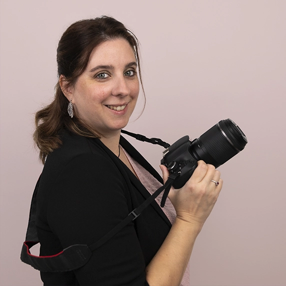 Portrait photographe professionnelle, femme souriante avec appareil photo, fond rose, Charlène photographe