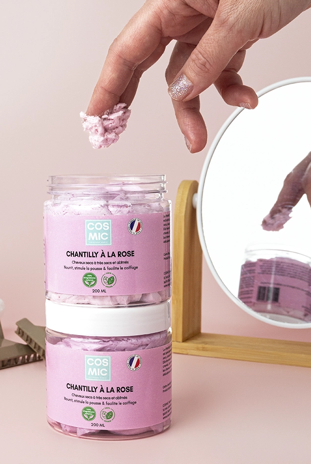 Chantilly à la rose COSMIC, main féminine prélevant la texture, miroir, photo lifestyle cosmétique.