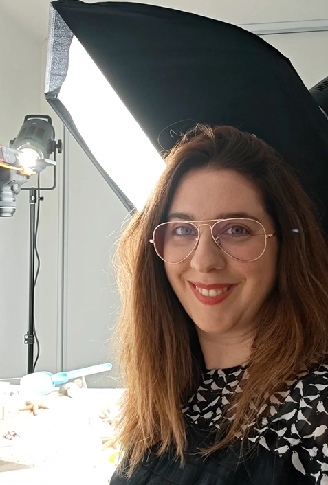 Portrait photographe femme souriante en studio, lunettes, lumière pro et softbox fond clair