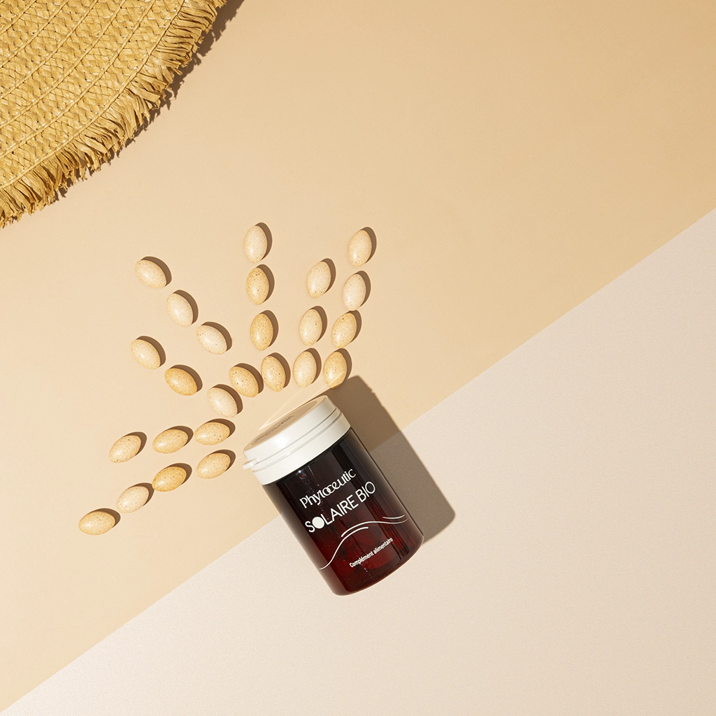 Complément Solaire Bio Phytoceutic comprimés dorés, chapeau paille, fond beige pour l'été.