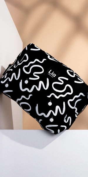 Pochette noire Lia Cosmétiques à motifs blancs, lumière graphique, accessoire beauté branding