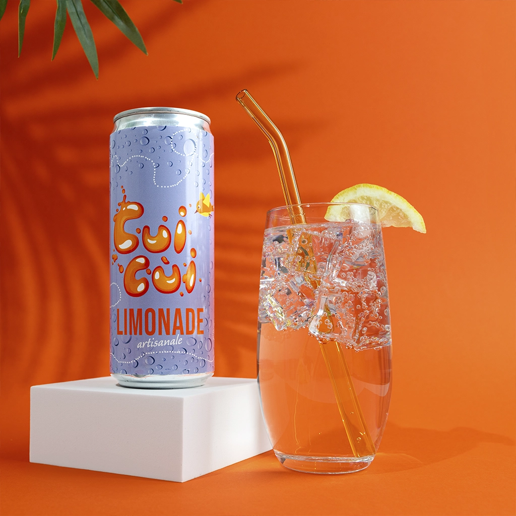 Canette limonade Cui cui avec verre glacé et citron sur fond orange vif.