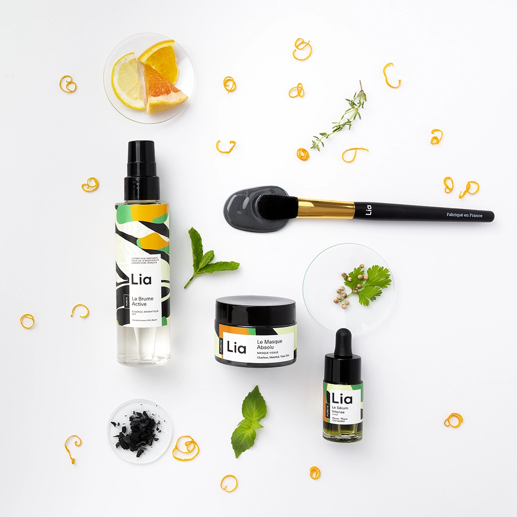 Gamme cosmétiques Lia avec agrumes, charbon actif et ingrédients naturels sur fond neutre.