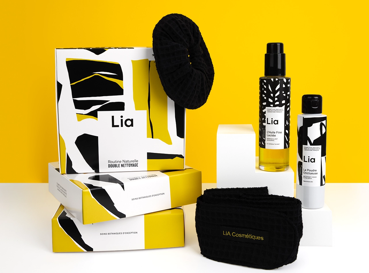 Coffret routine Lia double nettoyage avec produits, bandeau et serviette sur fond jaune.